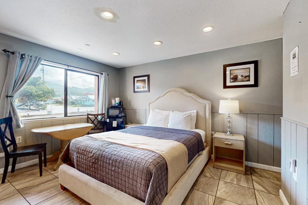 a bedroom with a bed and a desk and a window at Sea Treasures Inn #101 in Rockaway Beach