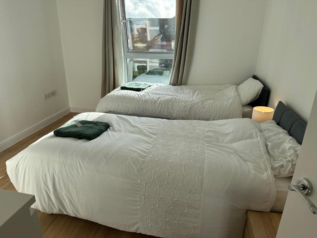 two white beds in a room with a window at Ganmos Place in Bracknell