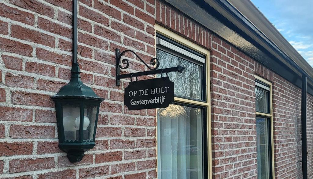 a sign on the side of a brick building with a street light at Op de Bult Gastenverblijf in Rasquert