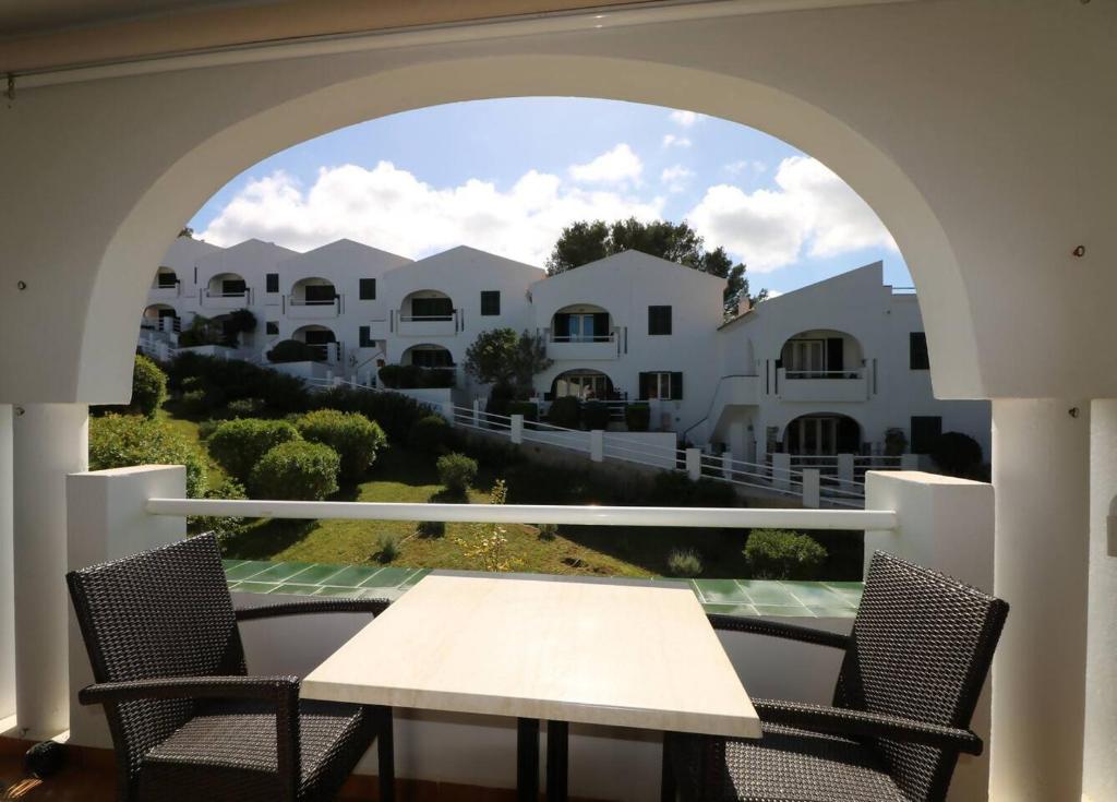 a table and chairs on a balcony with houses at Apartamento Complejo Pinimar in Port d'Addaia