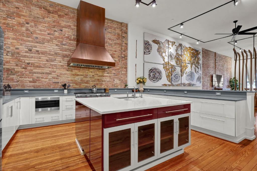 a kitchen with white cabinets and a brick wall at Luxe 220 Suite 3 in Wilmington