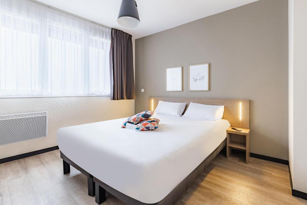 a large white bed with a stuffed animal on it at Appart'City Confort Amiens Gare in Amiens