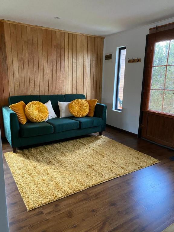 a living room with a blue couch with yellow pillows at Los Ciruelos Cabin in Calbuco