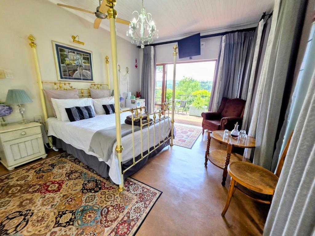 a bedroom with a bed and a chair and a table at Art Gallery Guest House in Haenertsburg