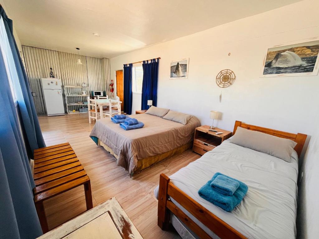 a bedroom with two beds and a kitchen with a table at El Atardecer Monoambiente in Puerto Pirámides