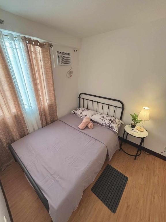 a bedroom with two beds and a table and a window at Arezzo Place Davao in Davao City