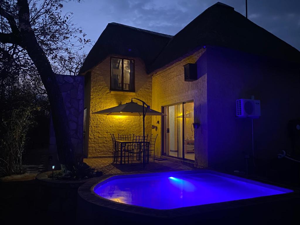a blue pool in front of a house at night at The Bush Hut in Hoedspruit