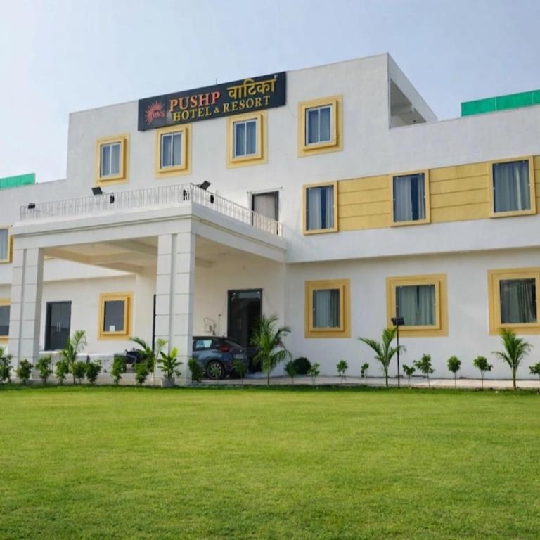 a building with a green lawn in front of it at Pushp Vatika Hotel & Resort in Thālera