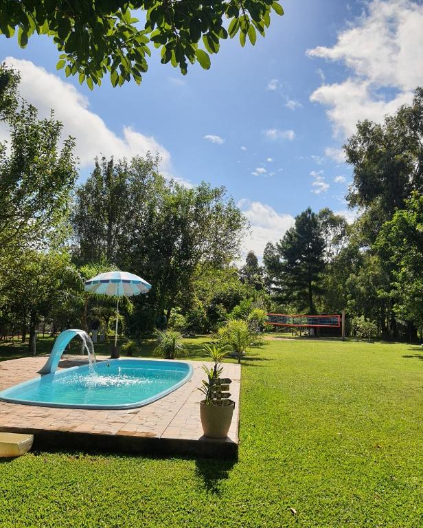 a swimming pool with an umbrella in a yard at Sítio do Berger 1 in São Gabriel
