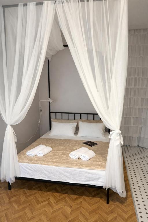a bedroom with a bed with white curtains at Sweet Home Tskaltubo Family Guesthouse Near Spa Park in Tsqaltubo