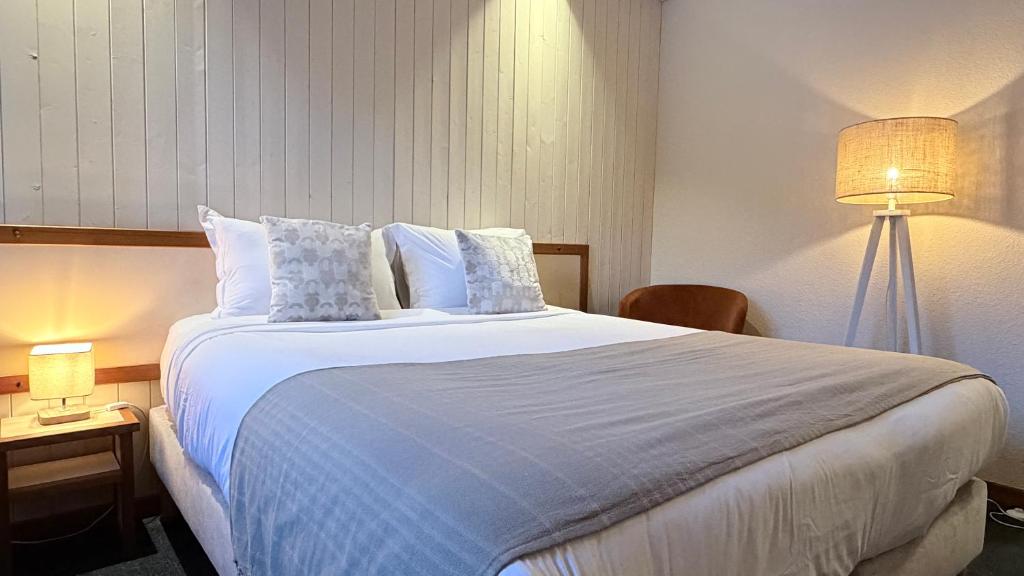 a hotel room with a large white bed with pillows at Hôtellerie du Roy - Restaurant Chez Robin in Sainte-Hélène-sur-Isère