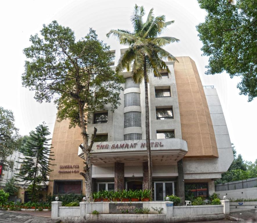 a building with a palm tree in front of it at The Samrat Hotel near Pune Railway Station in Pune