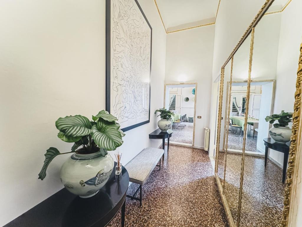 a hallway with a large mirror and a vase with a plant at Luxury Apartment in Lucca in Lucca