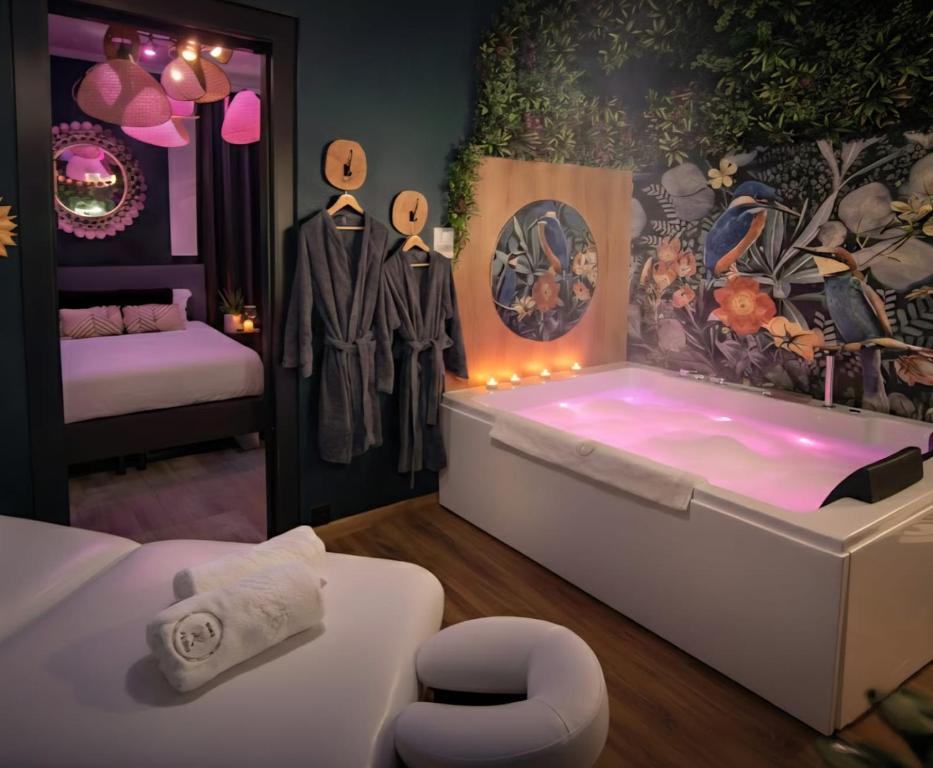a room with a bath tub with clothes on display at Suite Passion - Jacuzzi privé - Table massage in Saint-Étienne