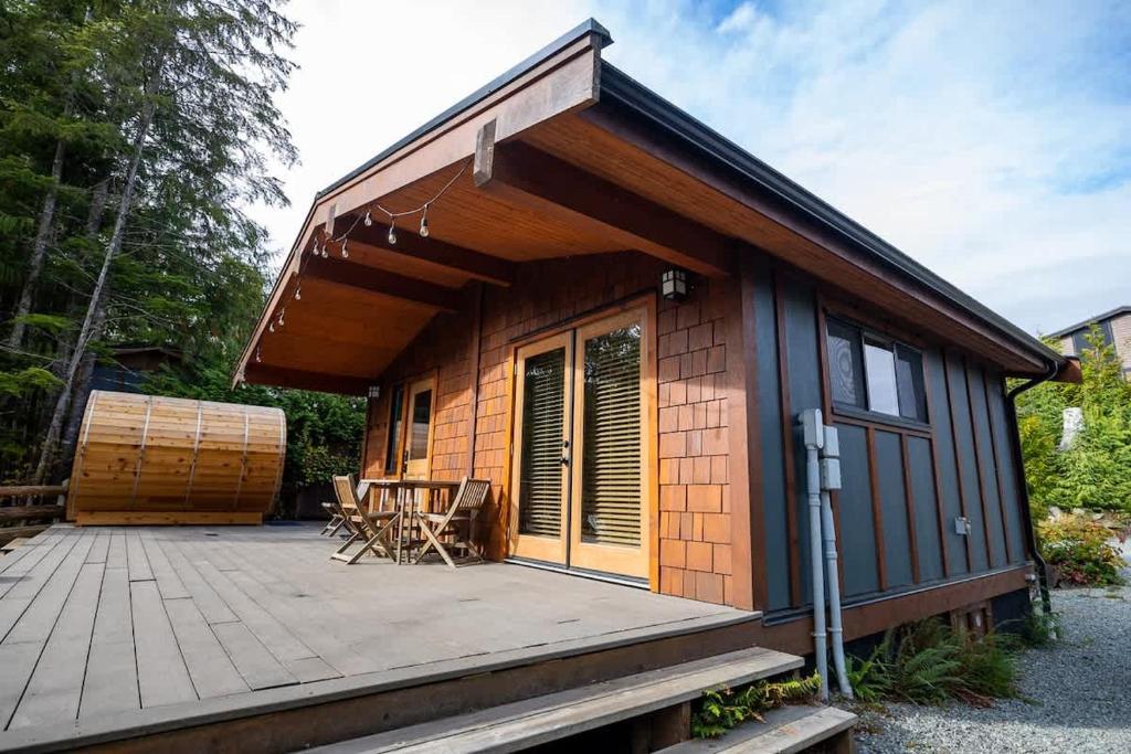 a small cabin with a deck with a patio at Explorer's Retreat Sauna & Bunkhouse & Fire pit in Port Renfrew