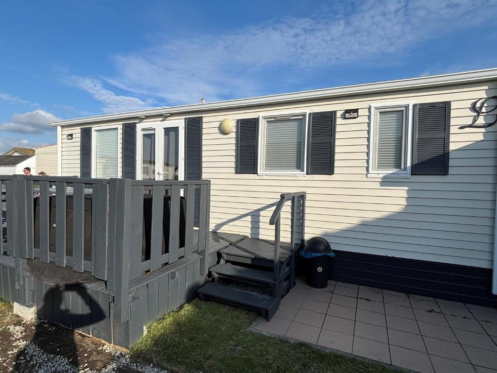 a mobile home with a staircase next to a fence at Seacottage Blankenberge-Wenduine in De Haan