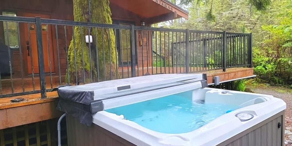 a hot tub on a balcony of a house at Hot tub Oasis Among Trees - Pet Friendly in Port Renfrew