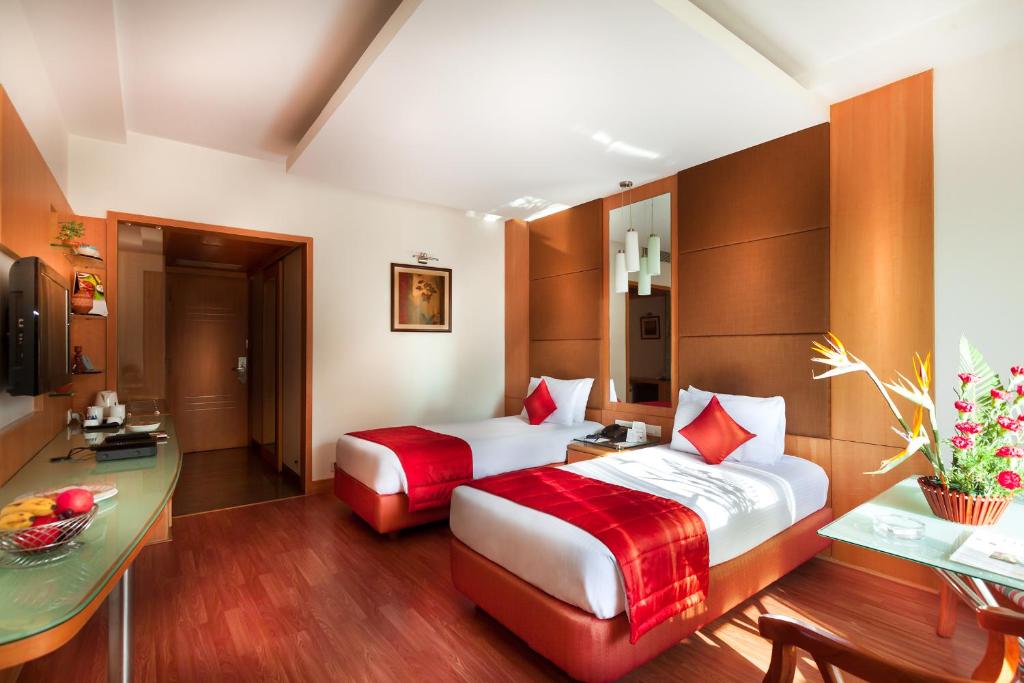 Habitación de hotel con 2 camas y escritorio en Regency Madurai by GRT Hotels, en Madurai
