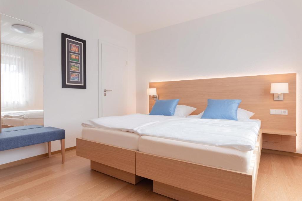 a bedroom with a large bed with blue pillows at Hotel Gästehaus Hirsch in Remseck-Pattonville