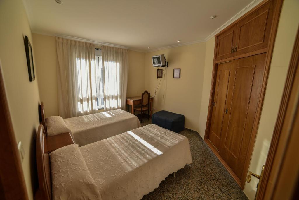 a bedroom with two beds and a wooden door at Casa Palomin in Ourense