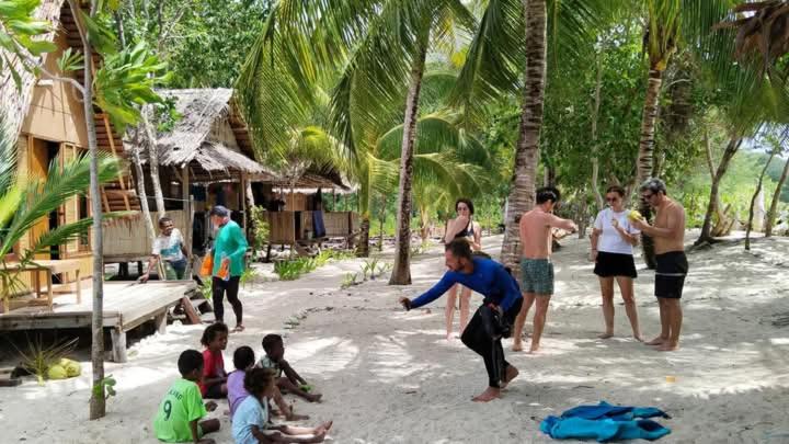 a group of people playing a game on the beach at Or Mandira Homestay in Pulau Penemu