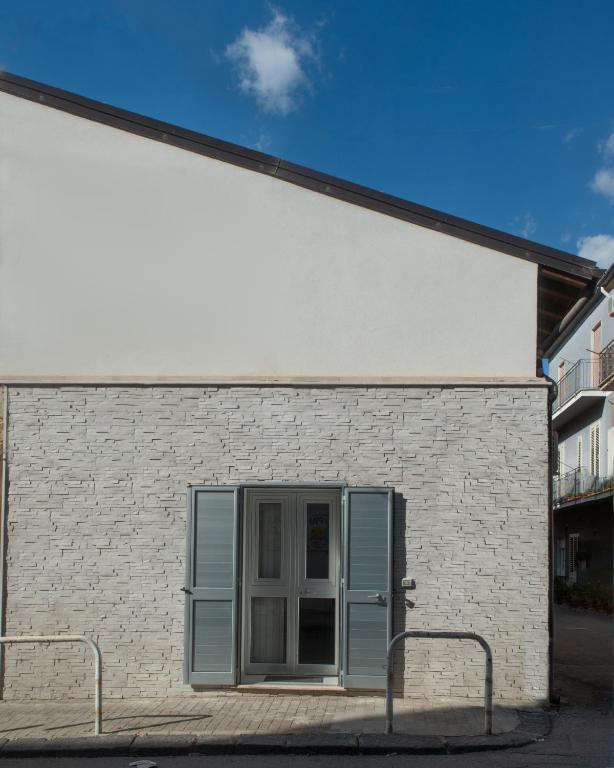 a white brick building with blue shutters on it at ASARO Camere in Campobello di Licata