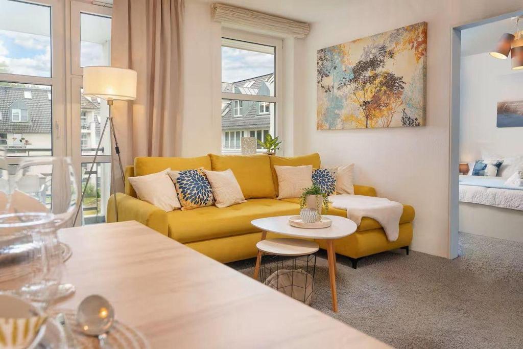a living room with a yellow couch and a table at RegioStyle-Apartment-mit-Meerblick-Balkon-Strand in Eckernförde