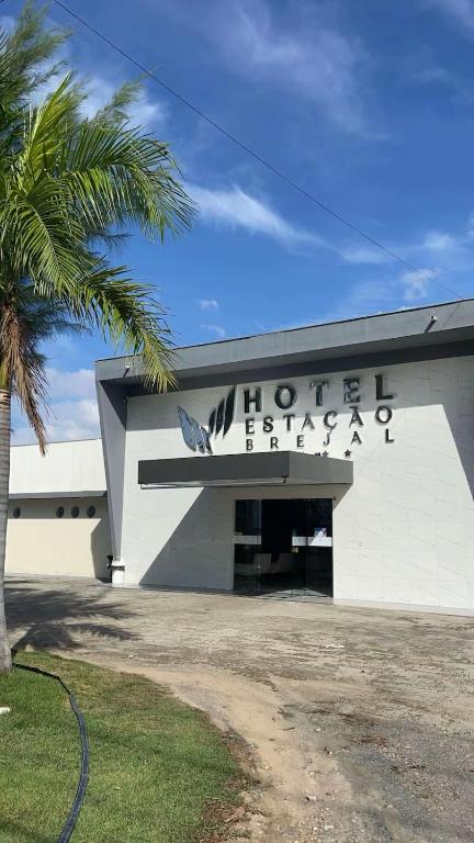 a white building with a sign on it with a palm tree at Hotel Estação Brejal in Brejo Santo