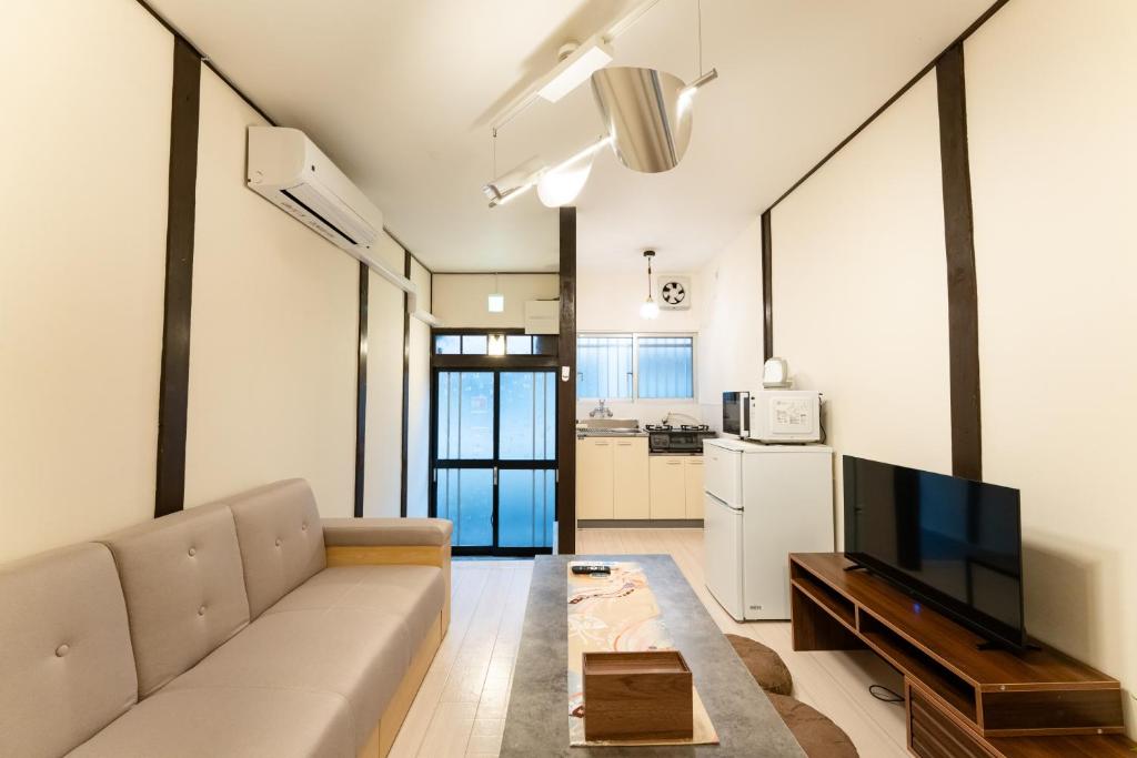 a living room with a couch and a tv at なんばや心斎橋にも直結の最大8名宿泊可能の広々メゾネット JPtrad 桔梗 in Osaka