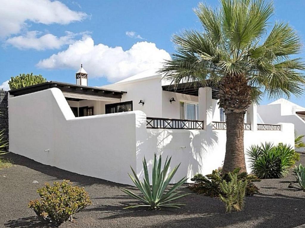 a white house with a palm tree in front of it at Studio Paraíso - Casa Paraíso Playa Blanca in Playa Blanca
