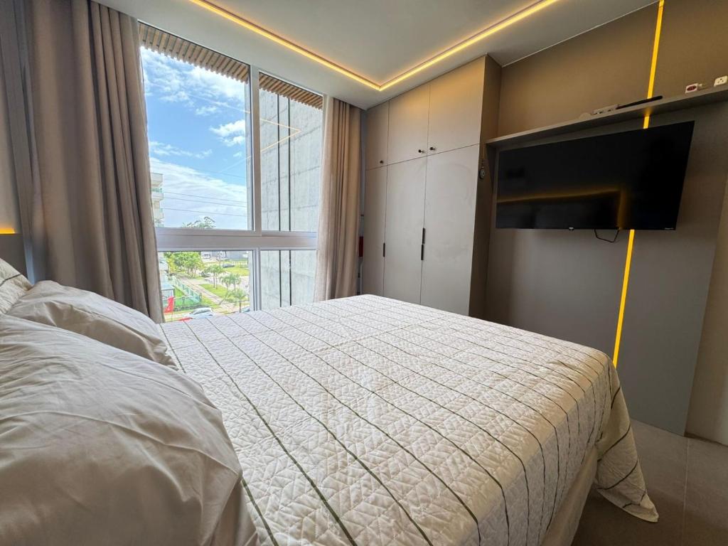 a bedroom with a bed and a large window at Loft Livin em Atlântida ao lado do Ramblas in Xangri-lá