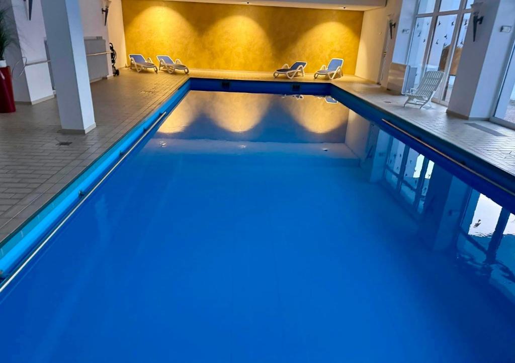 a swimming pool with blue water in a building at Schwarzwald Residenz Hirschen in Schönwald