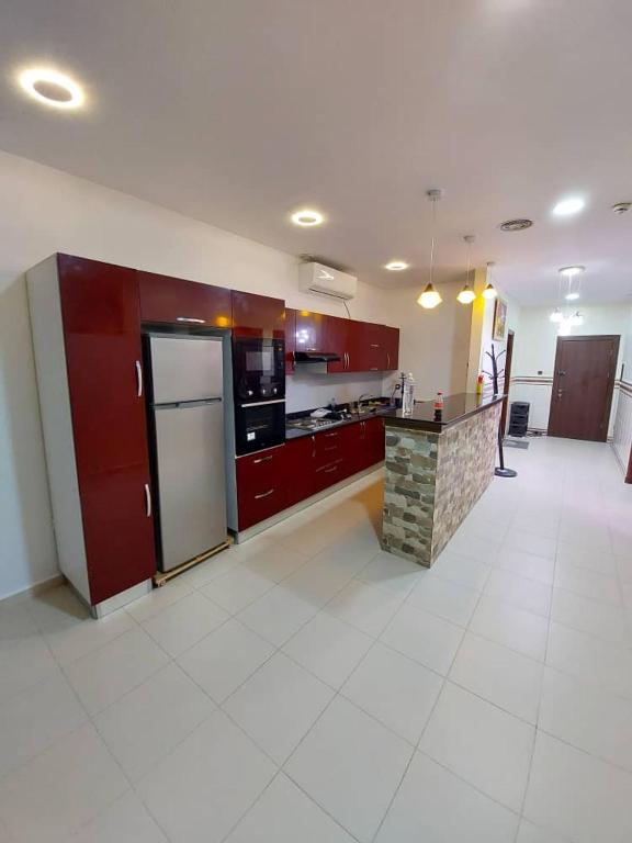 a large kitchen with red cabinets and a refrigerator at إقامة المول in Fort de lʼEau