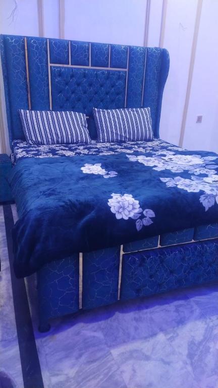 a blue bed with a blue bedspread with flowers on it at The 104-H in Faisalabad