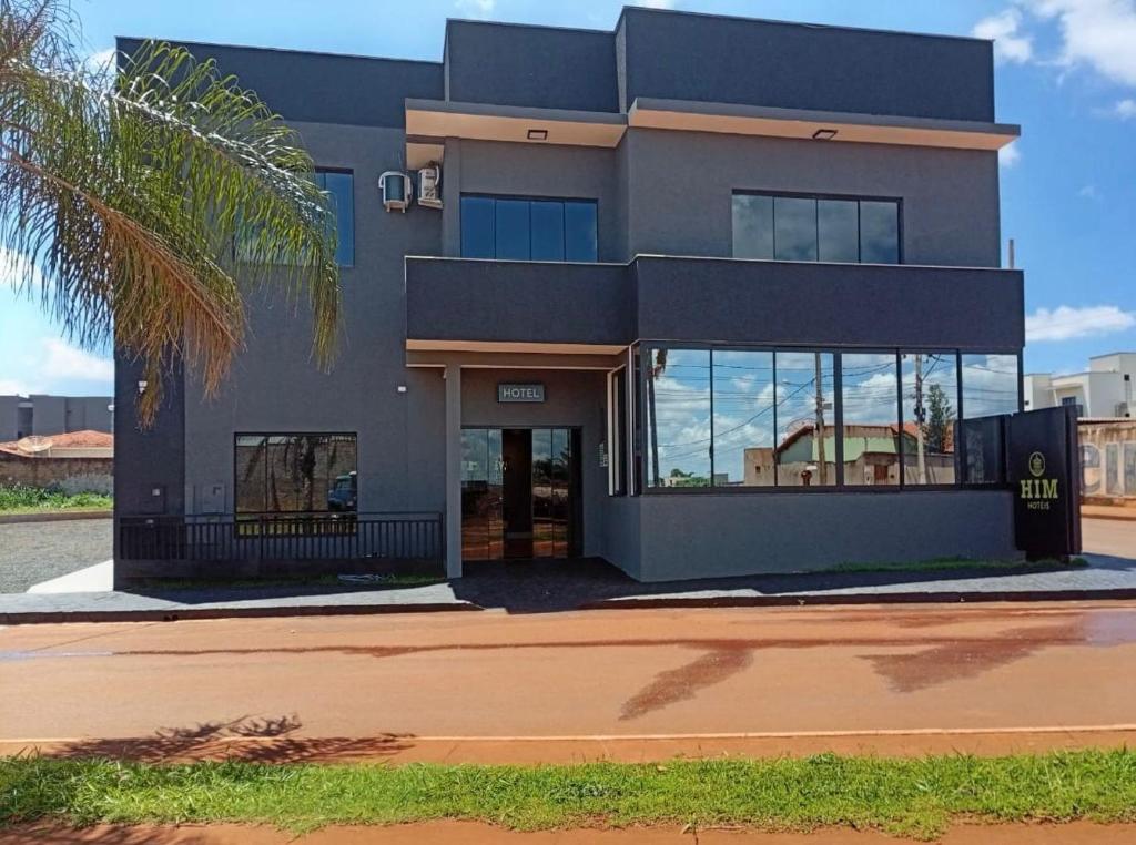 a building with a palm tree in front of it at Him Hotel in Iraí de Minas
