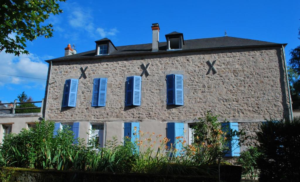a large brick building with blue shutters on it at Maison Le Feu Follet in Lormes