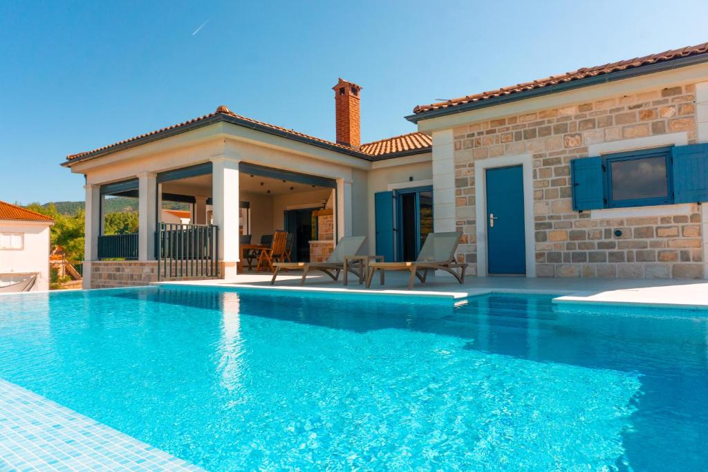 a swimming pool in front of a house at Vila JELSANA in Jelsa