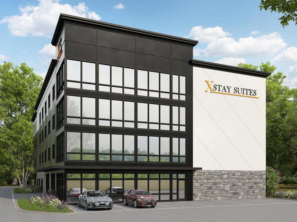 a building with two cars parked in a parking lot at XStay Suites Mansfield in Mansfield