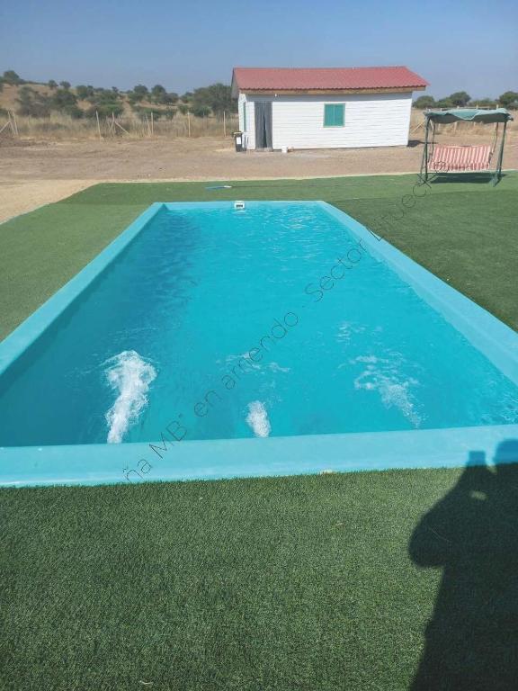 a blue swimming pool with a building in the background at Cabaña en Litueche - Parcela in Cartagena