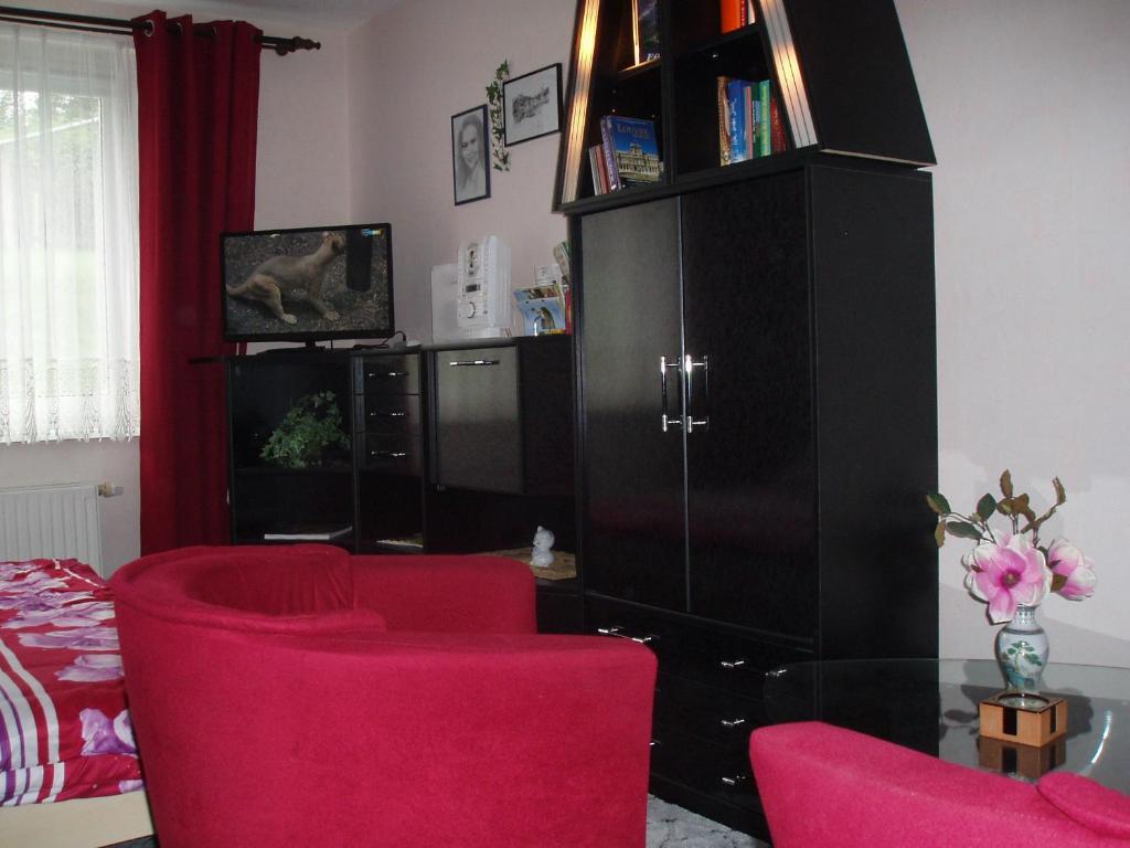 a living room with red chairs and a black cabinet at Ferienwohnung Anna in Greiz