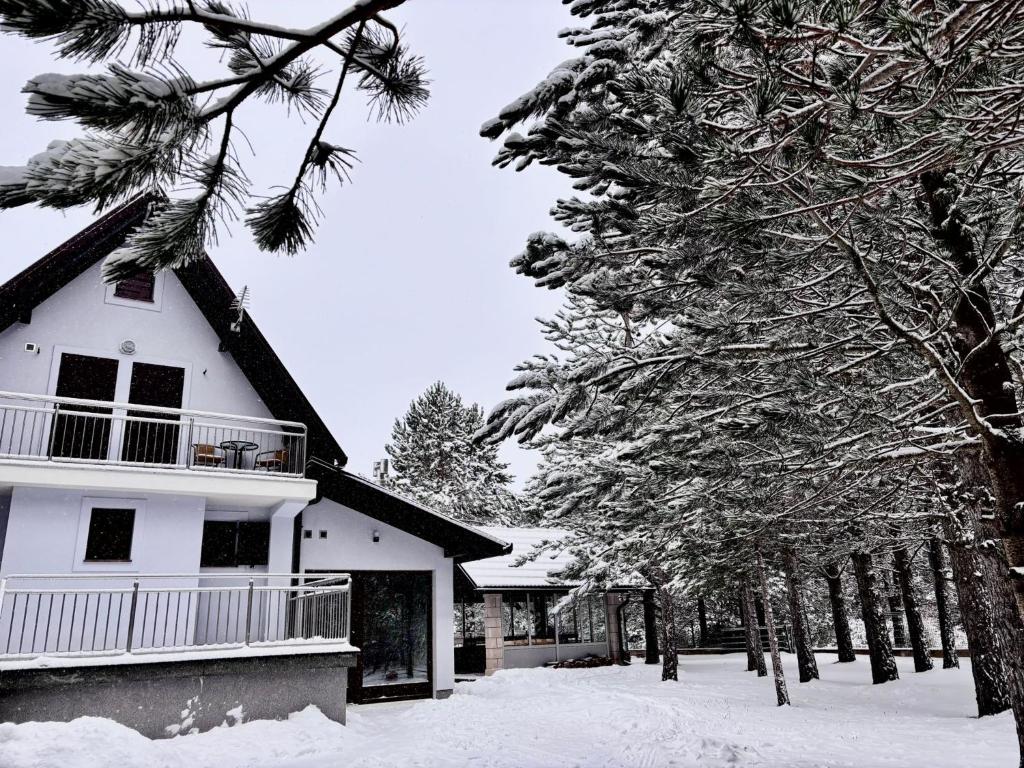a white house with snow covered trees in front of it at Calm Stay Blidinje in Blidinje