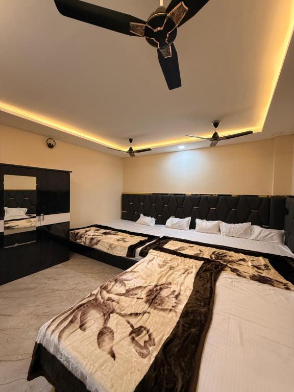 two beds in a room with a ceiling fan at Hotel Shivlok Inn in Ujjain