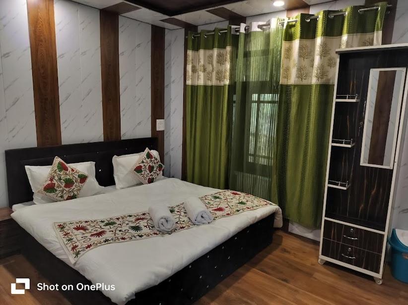 a bedroom with a large bed with green curtains at The sameer resort in Anantnāg