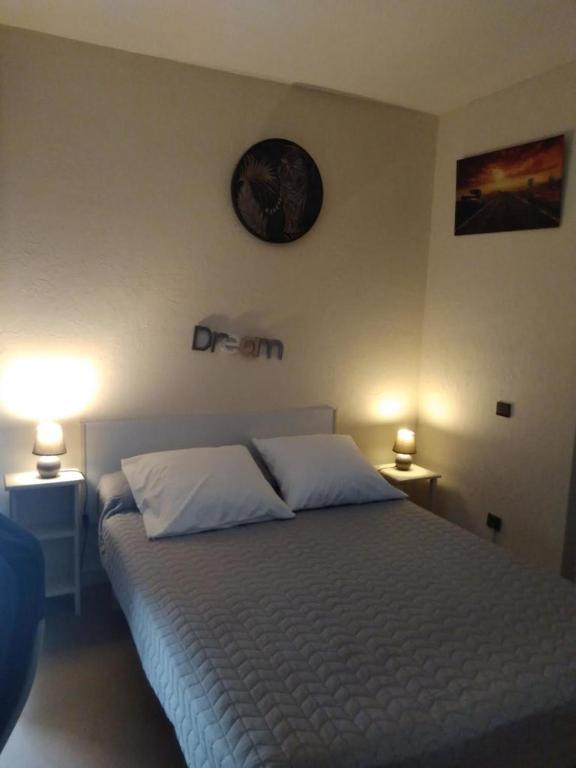 a bedroom with a bed with two pillows and a clock on the wall at Studio Barbotan in Barbotan-les-Thermes
