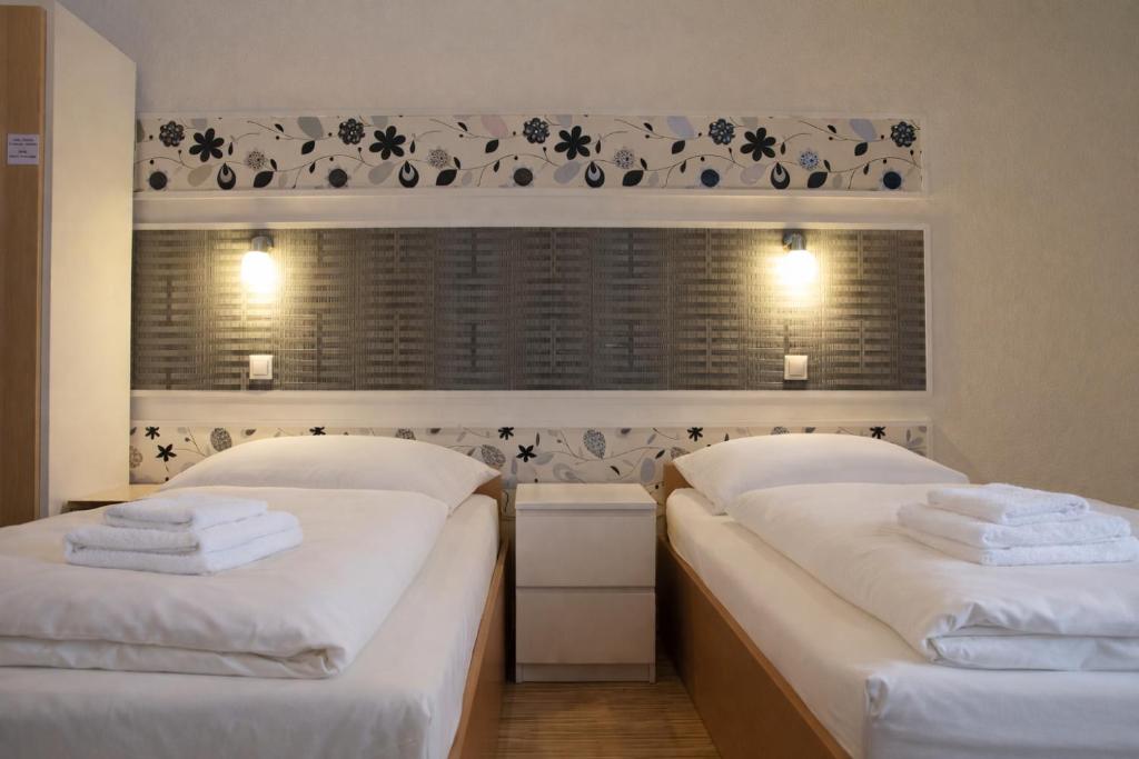 zwei Einzelbetten in einem Zimmer mit Fenster in der Unterkunft Pension Central Nuernberg-Fuerth in Fürth