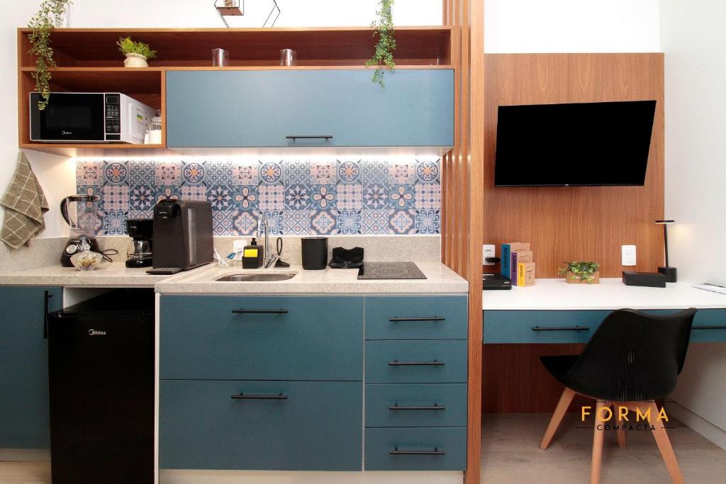 a kitchen with blue cabinets and a sink and a desk at Raízes Studios Tatuapé – Mitre 4 in São Paulo