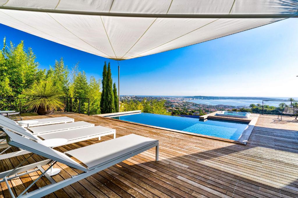 an outdoor deck with a pool and lounge chairs at Villa Bambou bei Cannes mit Blick auf Cap Antibes in Vallauris