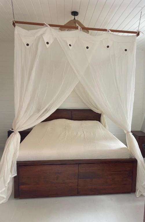 a bed with a mosquito net on top of it at Bungalow sur la plage in Le Carbet