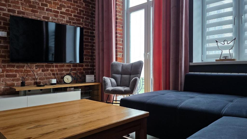 a living room with a couch and a tv on a brick wall at !! VIP Apartament Pod BIESZCZADAMI !! in Sanok