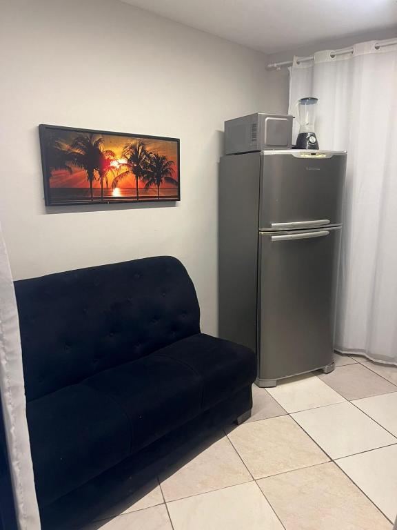 ein schwarzes Sofa in einem Zimmer mit einem Kühlschrank in der Unterkunft apt 112 in Teresina